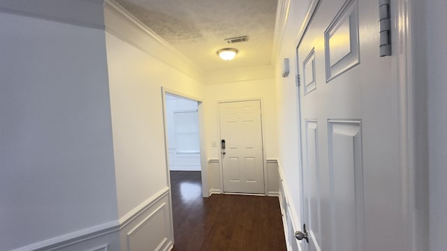 corridor featuring visible vents, a textured ceiling, crown molding, and dark wood-type flooring