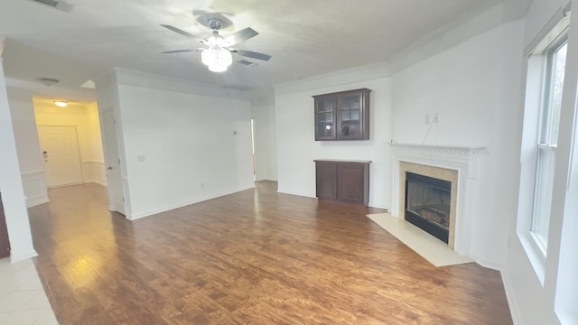 unfurnished living room with crown molding, ceiling fan, a fireplace with flush hearth, and wood finished floors