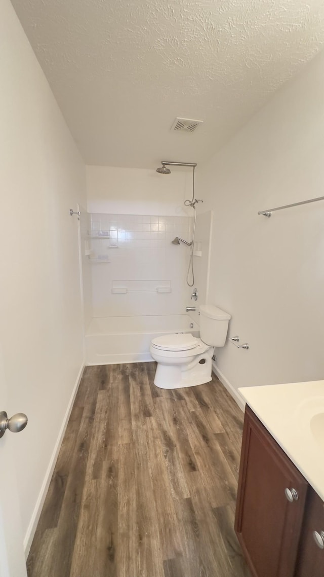 bathroom with a textured ceiling, visible vents, toilet, wood finished floors, and vanity