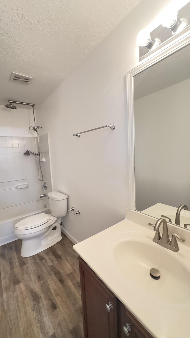 full bathroom with a textured ceiling, visible vents, toilet, shower / bath combination, and wood finished floors
