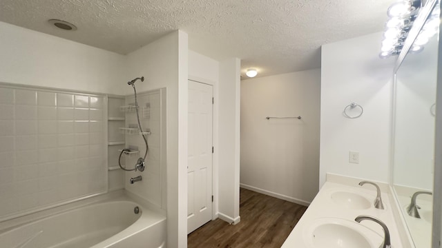 full bathroom featuring wood finished floors, shower / washtub combination, a textured ceiling, and a sink