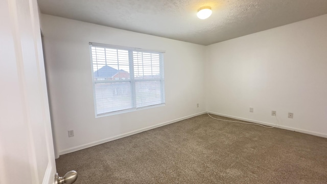carpeted spare room with a textured ceiling and baseboards