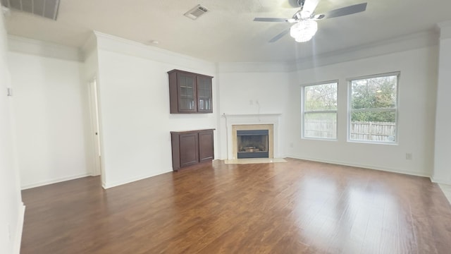 unfurnished living room featuring dark wood-style flooring, visible vents, ceiling fan, and crown molding