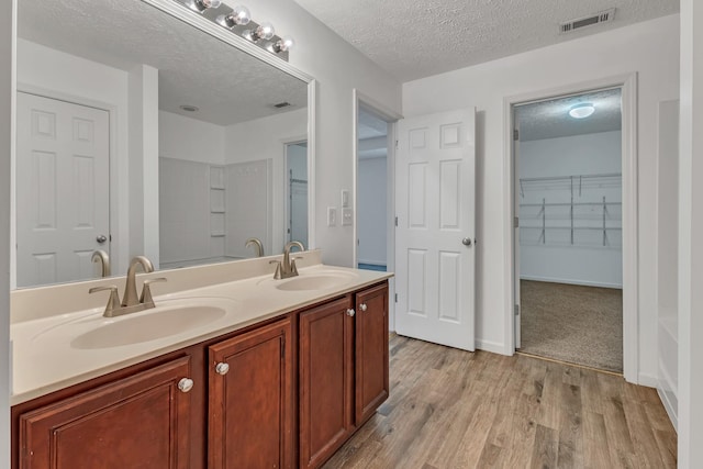 7347 Autumn Crossing Way, Brentwood, TN 37027 - bathroom featuring double vanity, a textured ceiling, wood finished floors, a shower, and a walk in closet