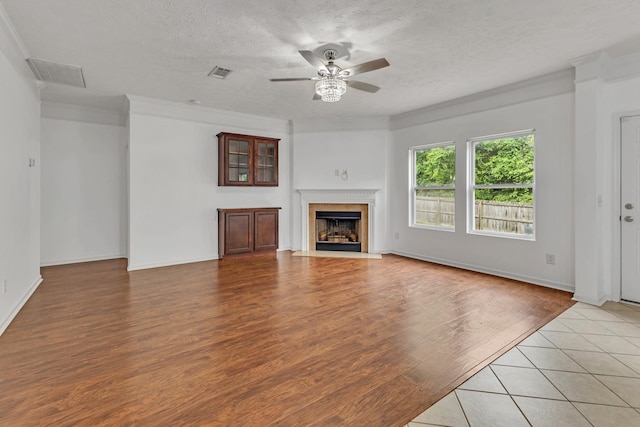7347 Autumn Crossing Way, Brentwood, TN 37027 - unfurnished living room with a ceiling fan, light wood-style floors, a fireplace with flush hearth, a textured ceiling, and crown molding