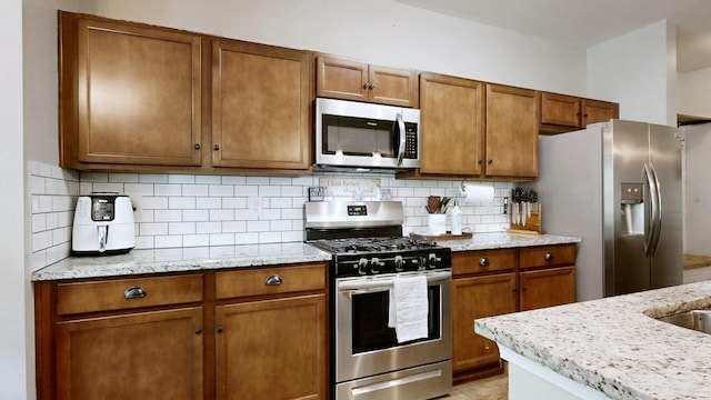 524 Burchell Ln, Columbia, TN 38401 - kitchen with brown cabinets, stainless steel appliances, light stone countertops, and decorative backsplash