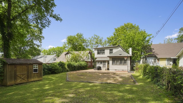 rear view of house featuring an outdoor structure, a patio, a yard, and a shed