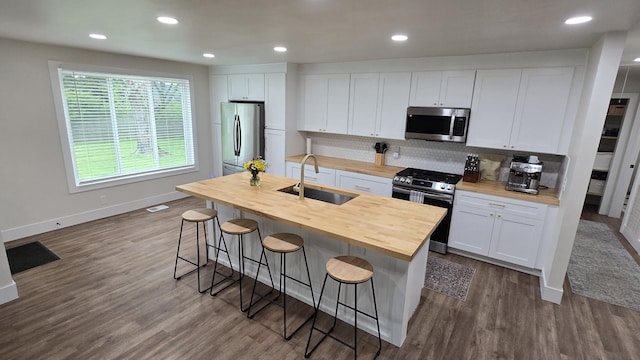 kitchen featuring appliances with stainless steel finishes, butcher block counters, dark wood-style floors, and a sink