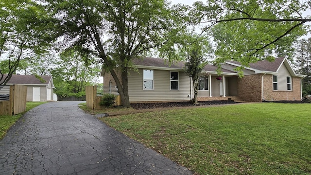 ranch-style home with brick siding, fence, a shingled roof, driveway, and a front yard