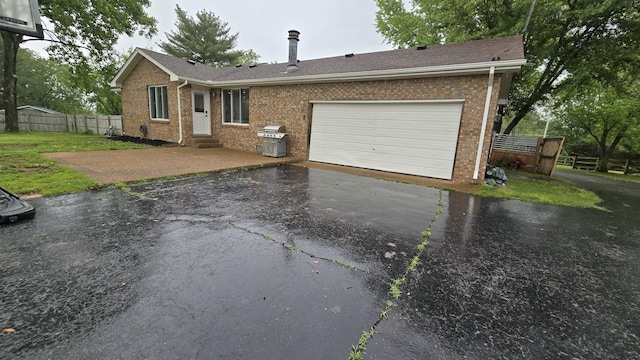view of front facade with brick siding, fence, entry steps, driveway, and an attached garage