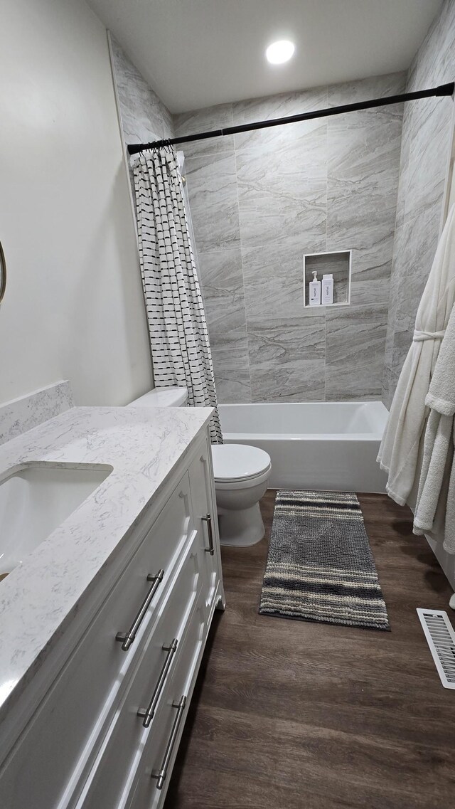 full bathroom with wood finished floors, toilet, vanity, visible vents, and shower / tub combo with curtain