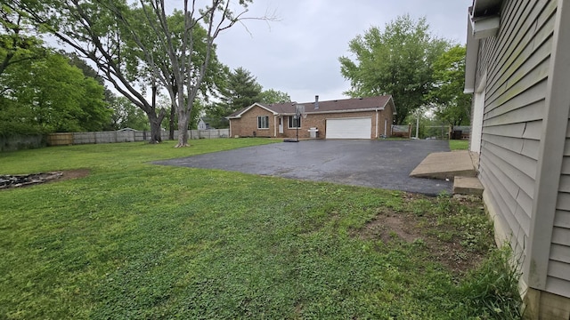 view of yard featuring fence and aphalt driveway