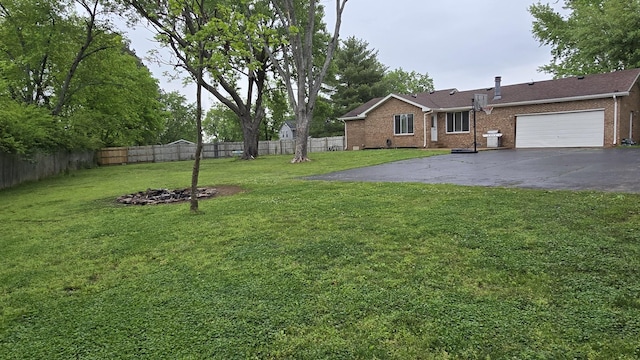 view of yard featuring fence, driveway, and an attached garage