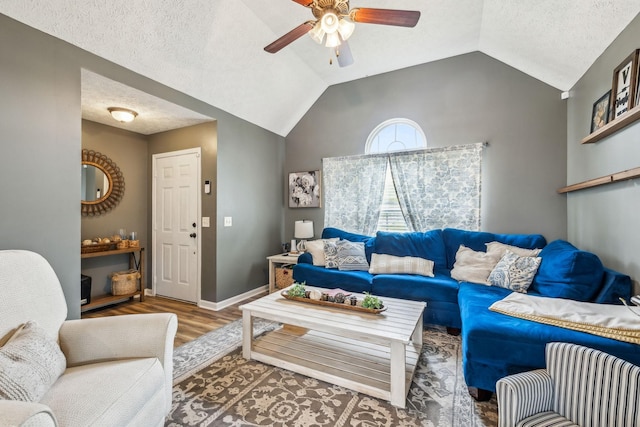 living area with wood finished floors, baseboards, a ceiling fan, a textured ceiling, and lofted ceiling