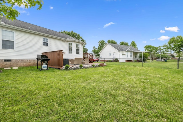 rear view of property with a lawn, a wooden deck, and a fenced backyard