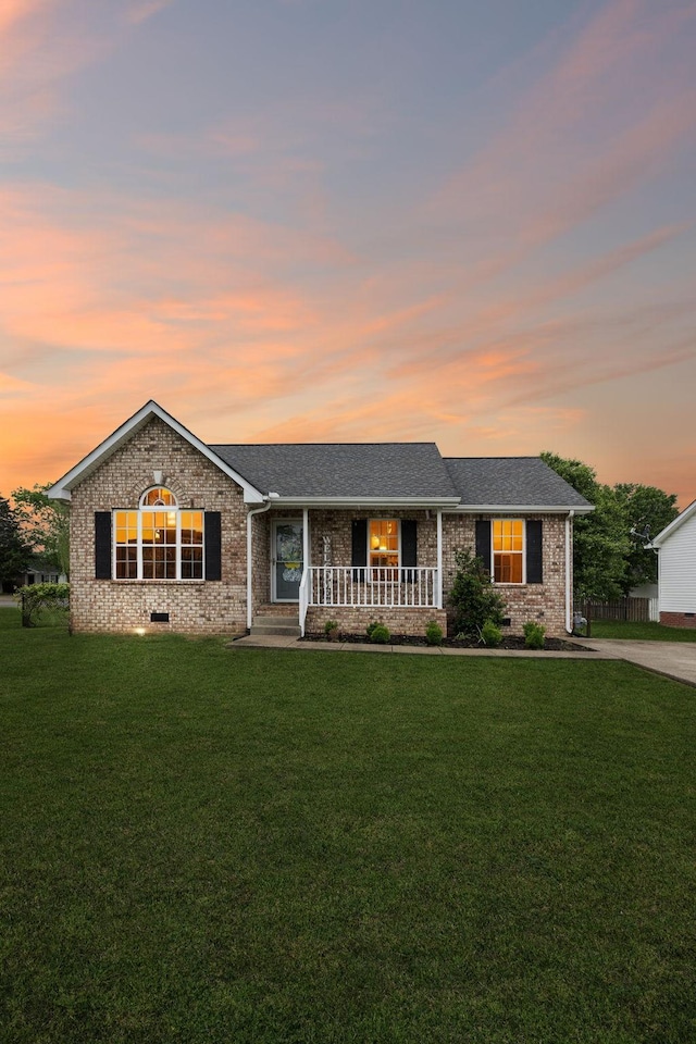 ranch-style home with covered porch, brick siding, and a front lawn
