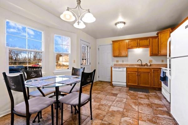 kitchen featuring white appliances, a chandelier, brown cabinetry, and light countertops