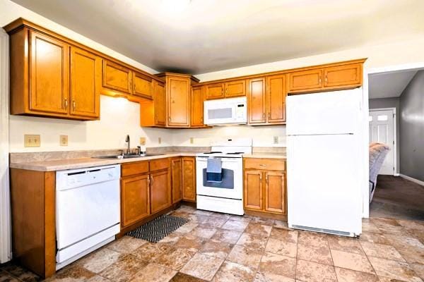 kitchen with white appliances, a sink, light countertops, and brown cabinets
