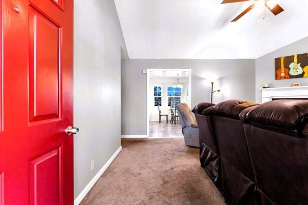 living room featuring a ceiling fan, carpet floors, baseboards, and vaulted ceiling