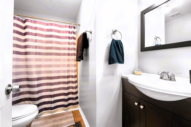 bathroom featuring vanity, toilet, curtained shower, wood finished floors, and baseboards
