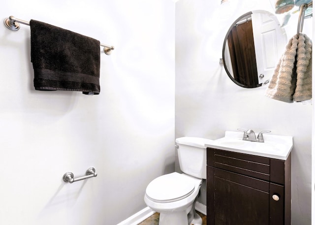 bathroom with toilet, vanity, and baseboards