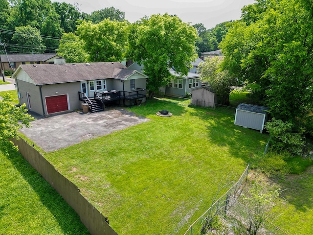 view of yard with a storage shed, a wooden deck, an outbuilding, an attached garage, and an outdoor fire pit
