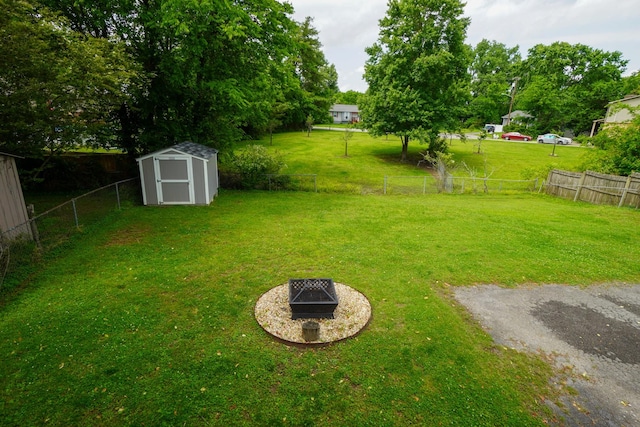 view of yard featuring a storage shed, an outdoor structure, and a fire pit