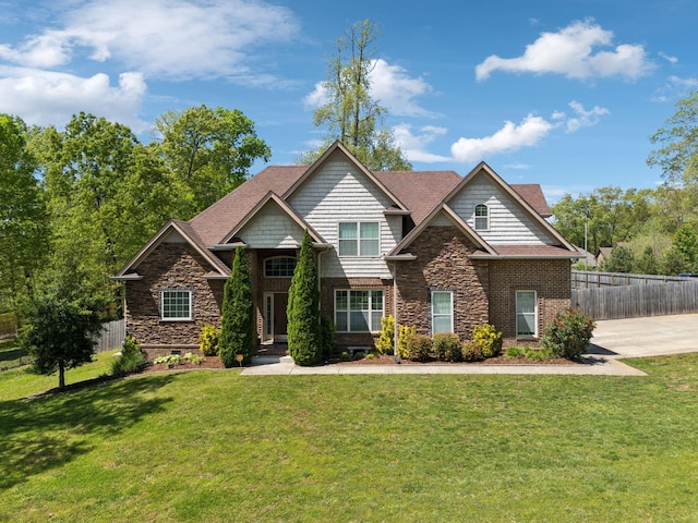 craftsman-style house with a front lawn, stone siding, and fence