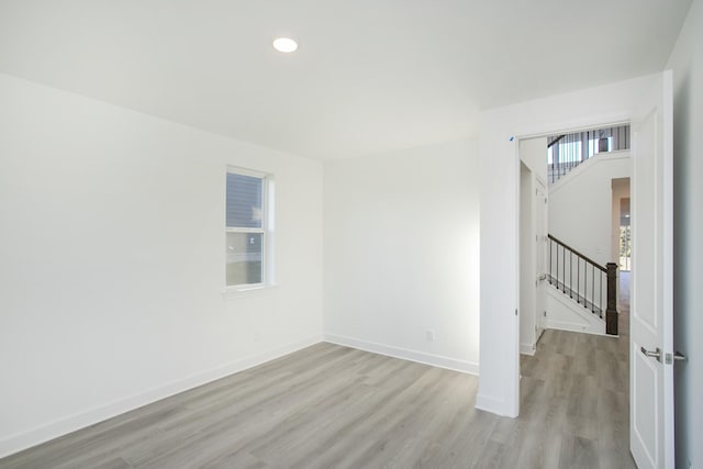 empty room with light wood-type flooring, baseboards, recessed lighting, and stairs