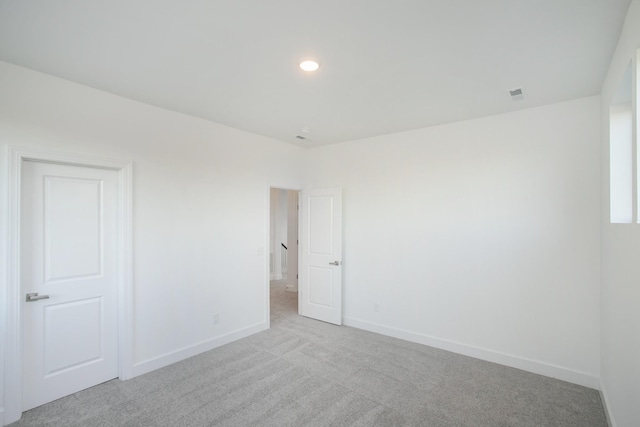 spare room featuring recessed lighting, visible vents, light carpet, and baseboards