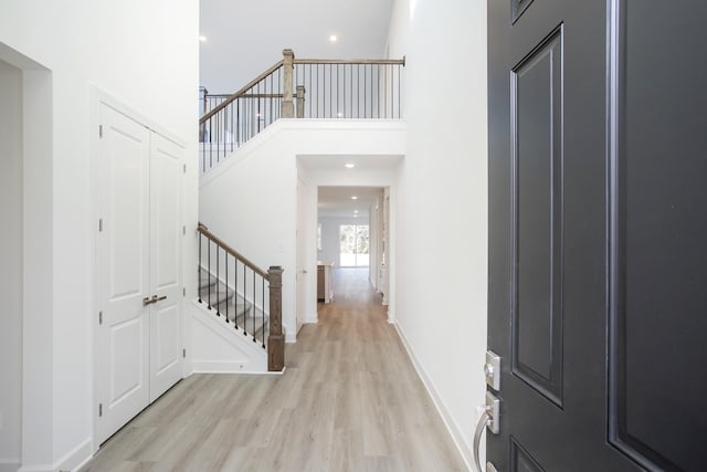 entrance foyer with light wood finished floors, a high ceiling, recessed lighting, and baseboards