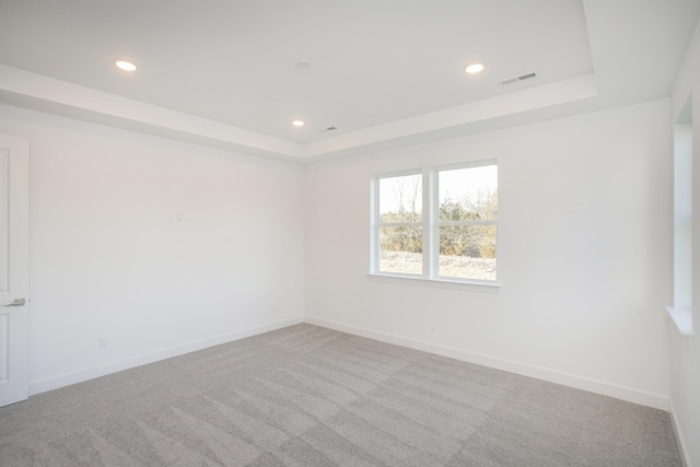 empty room with visible vents, recessed lighting, and a tray ceiling