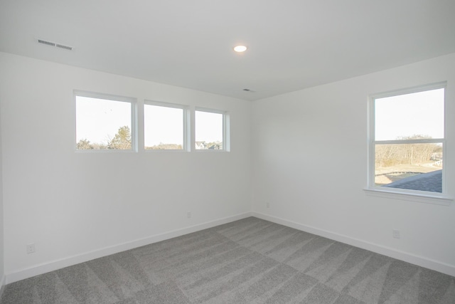 empty room featuring visible vents, baseboards, light colored carpet, and a healthy amount of sunlight