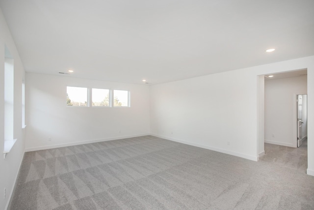 spare room featuring baseboards, recessed lighting, and light colored carpet