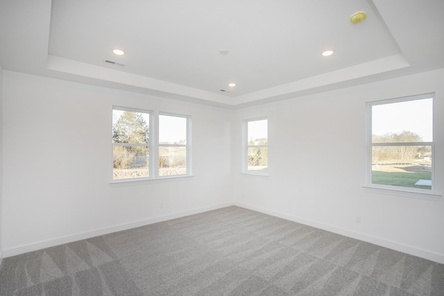 carpeted spare room featuring a raised ceiling, recessed lighting, and baseboards