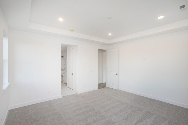 empty room with recessed lighting, a tray ceiling, visible vents, light carpet, and baseboards