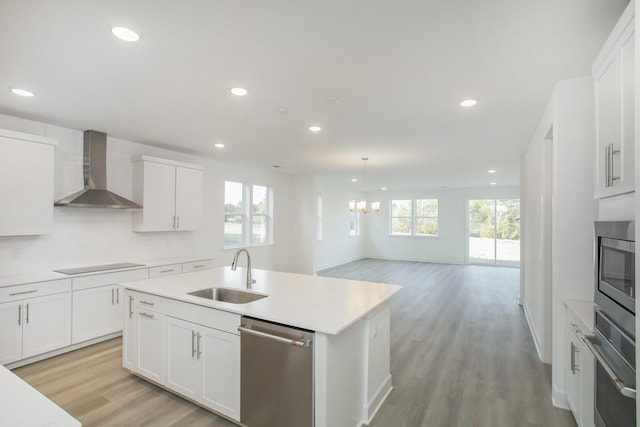 kitchen featuring a sink, stainless steel appliances, light wood-style floors, wall chimney range hood, and light countertops
