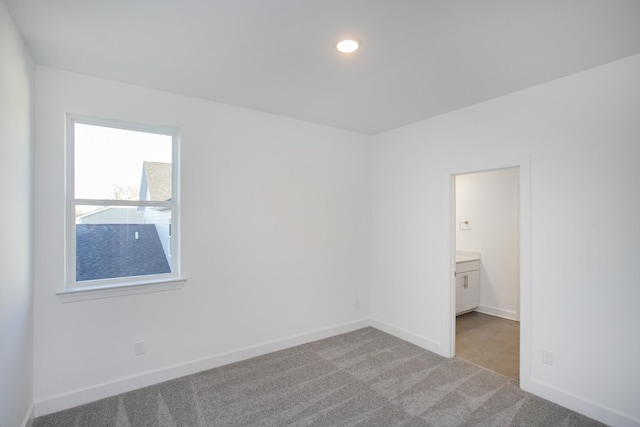 empty room featuring baseboards, recessed lighting, and light colored carpet