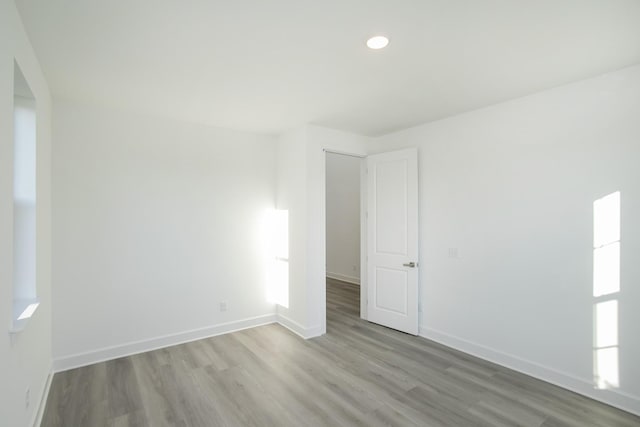 spare room with baseboards, recessed lighting, and wood finished floors