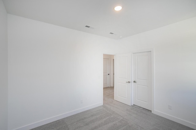 spare room with visible vents, light carpet, and baseboards