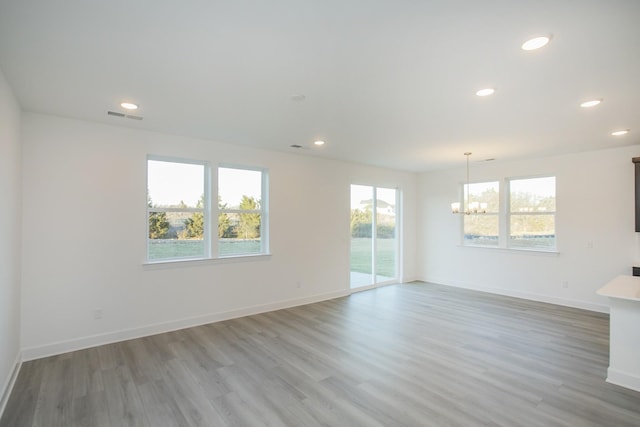 unfurnished living room with recessed lighting, light wood finished floors, baseboards, visible vents, and a notable chandelier