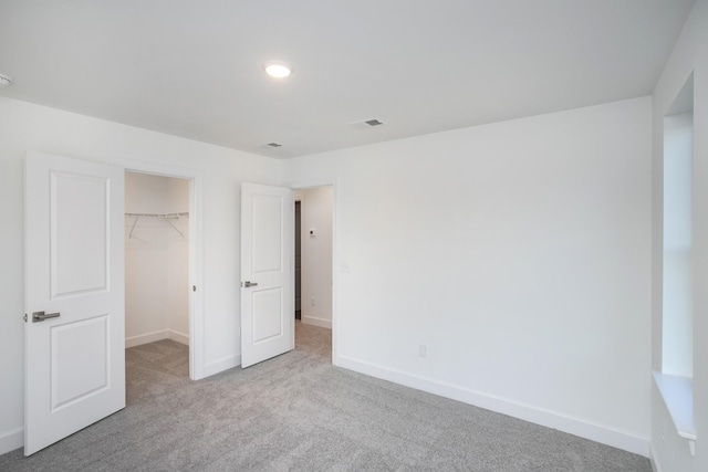 unfurnished bedroom featuring baseboards, a spacious closet, carpet floors, and a closet