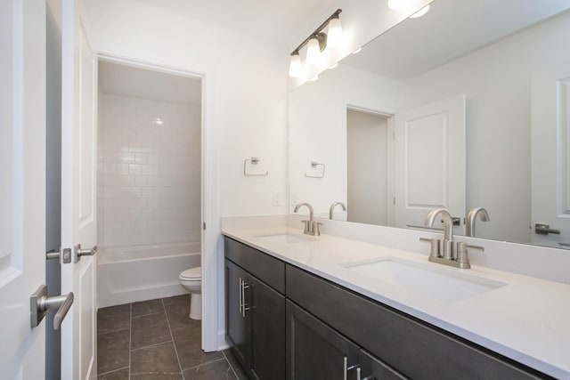 full bathroom featuring toilet, double vanity, a sink, and tile patterned floors
