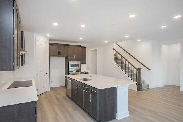 kitchen featuring recessed lighting, a sink, a center island with sink, light wood-style flooring, and appliances with stainless steel finishes