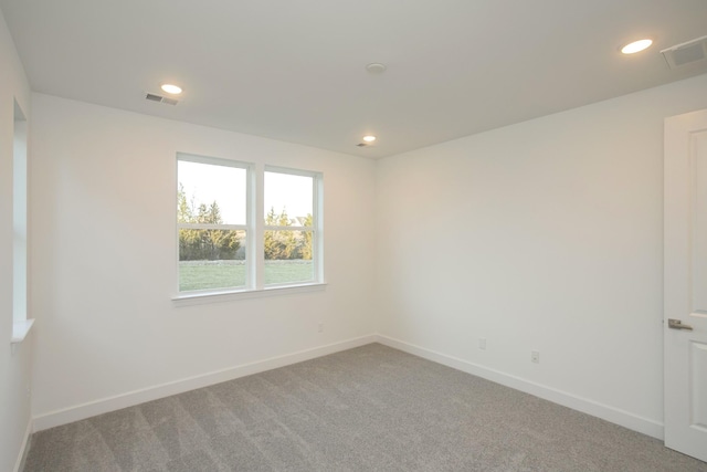 empty room featuring light colored carpet, visible vents, recessed lighting, and baseboards