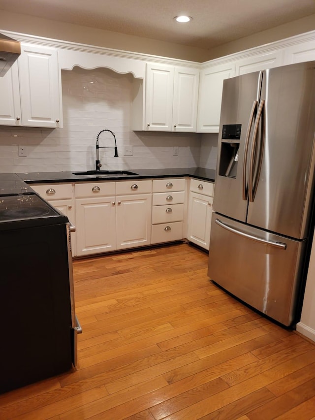 kitchen with white cabinets, stainless steel refrigerator with ice dispenser, range, and a sink