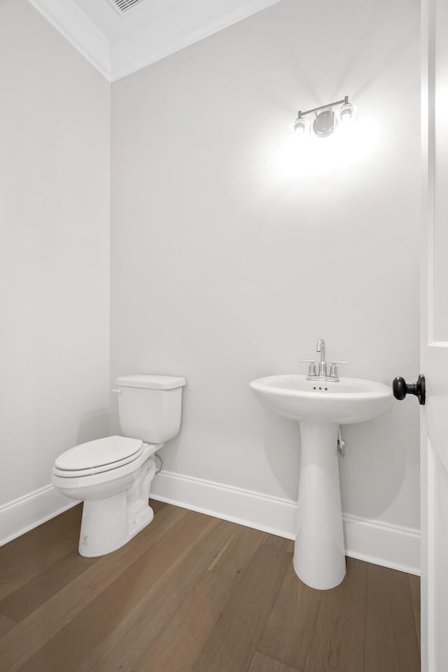 bathroom with wood finished floors, toilet, and baseboards