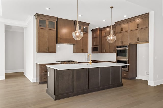 kitchen with appliances with stainless steel finishes, light wood-style flooring, and baseboards
