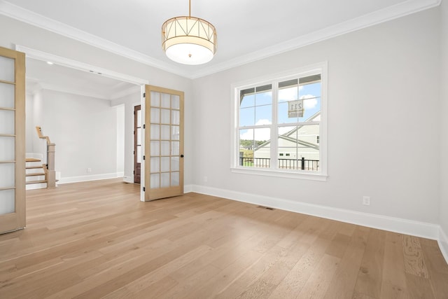 spare room with stairway, light wood-style floors, visible vents, baseboards, and ornamental molding