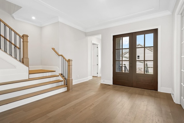 foyer entrance featuring crown molding, french doors, baseboards, wood finished floors, and stairs